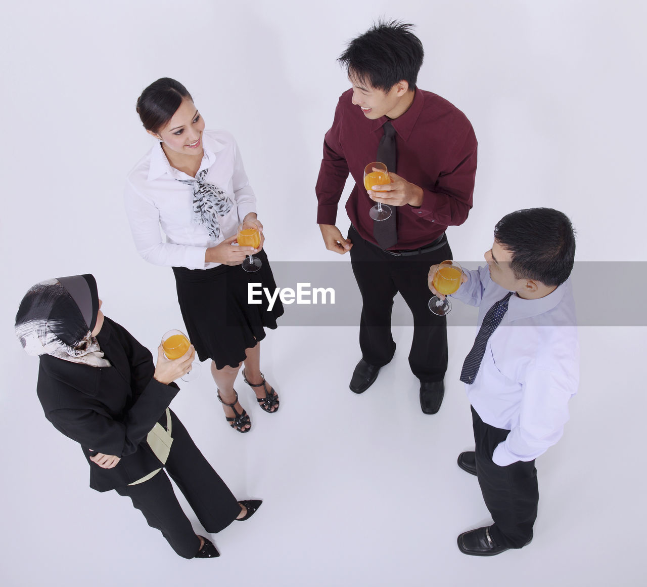 High angle view of business people holding drinks while standing over white background
