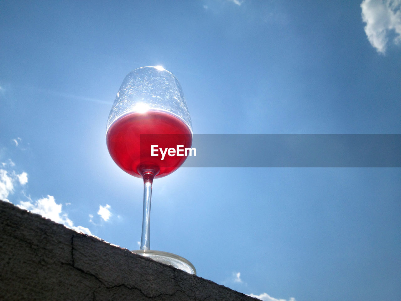 Low angle view of wine glass against blue sky