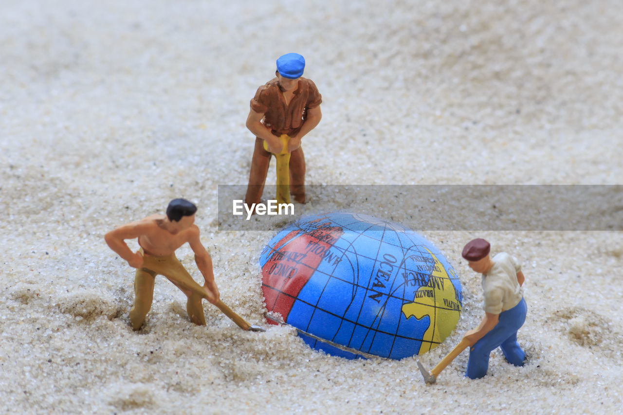 Figurine and globe on sand at beach