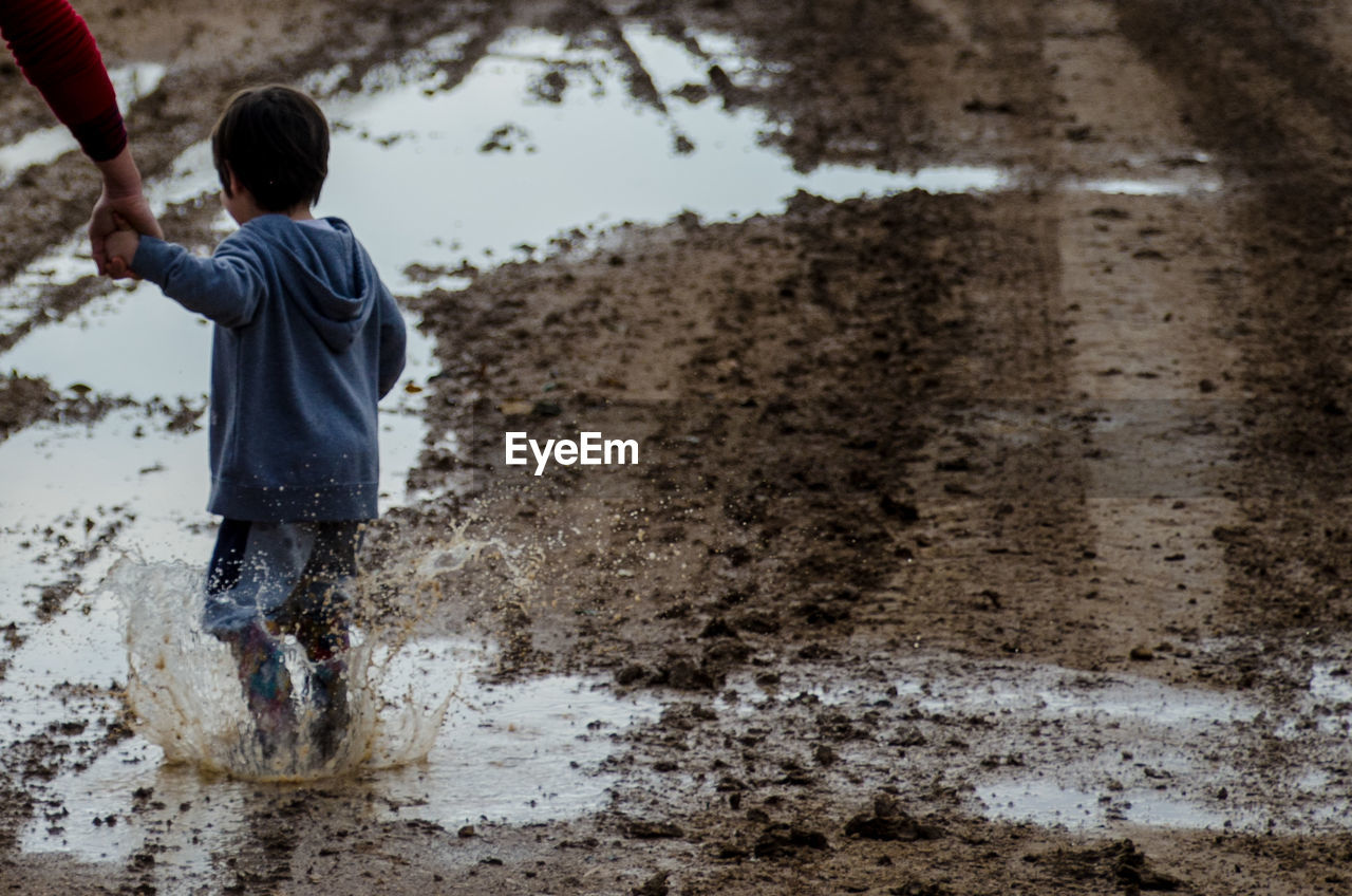 Adult and boy walking on wet sand