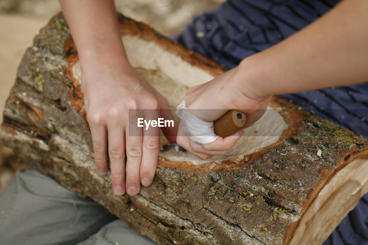 Midsection of man carving log