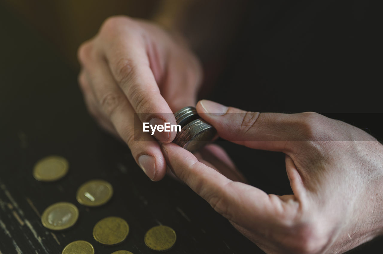 Business man counting money. rich male hands holds and count coins of different euros on table