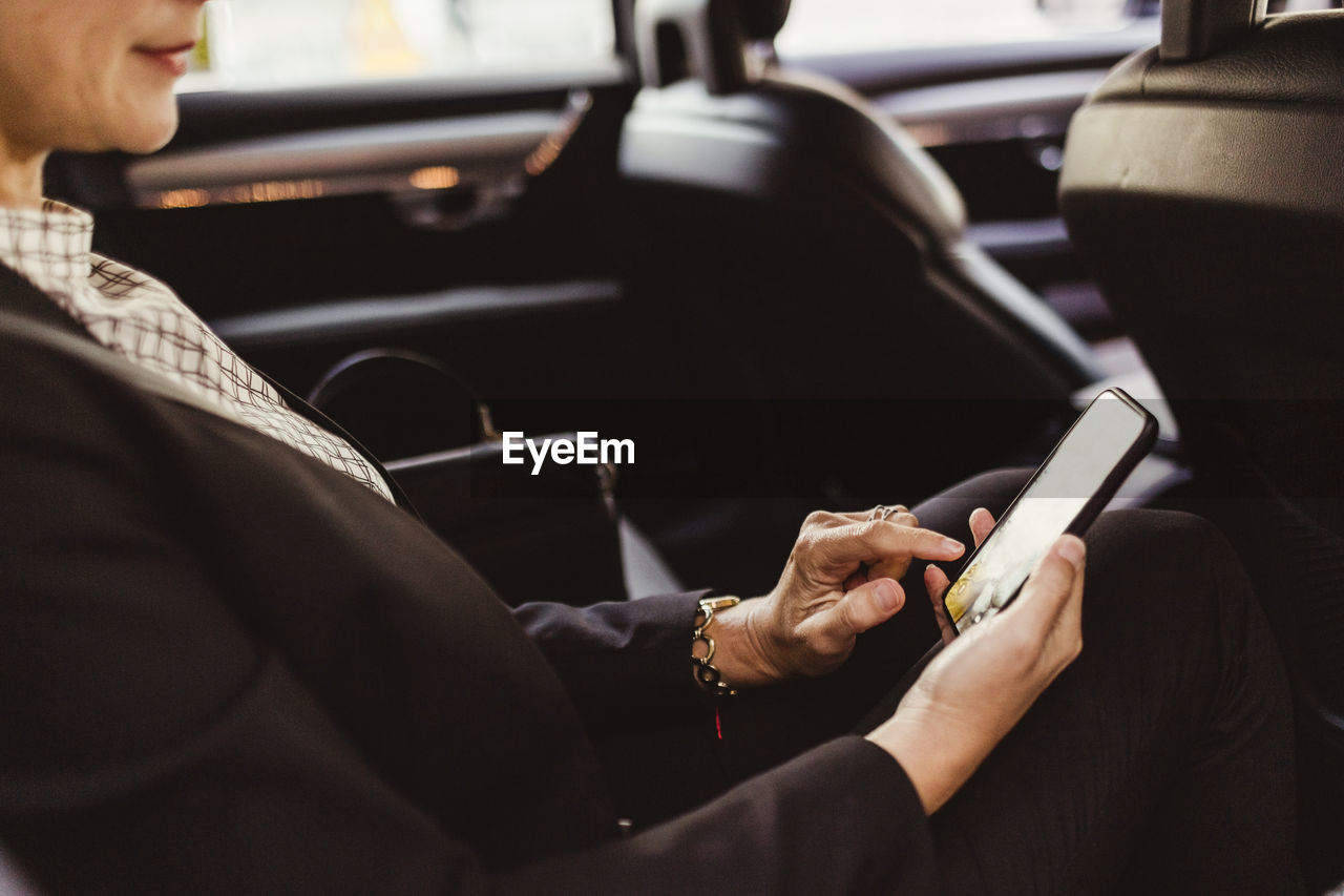 Midsection of entrepreneur surfing net while sitting in car