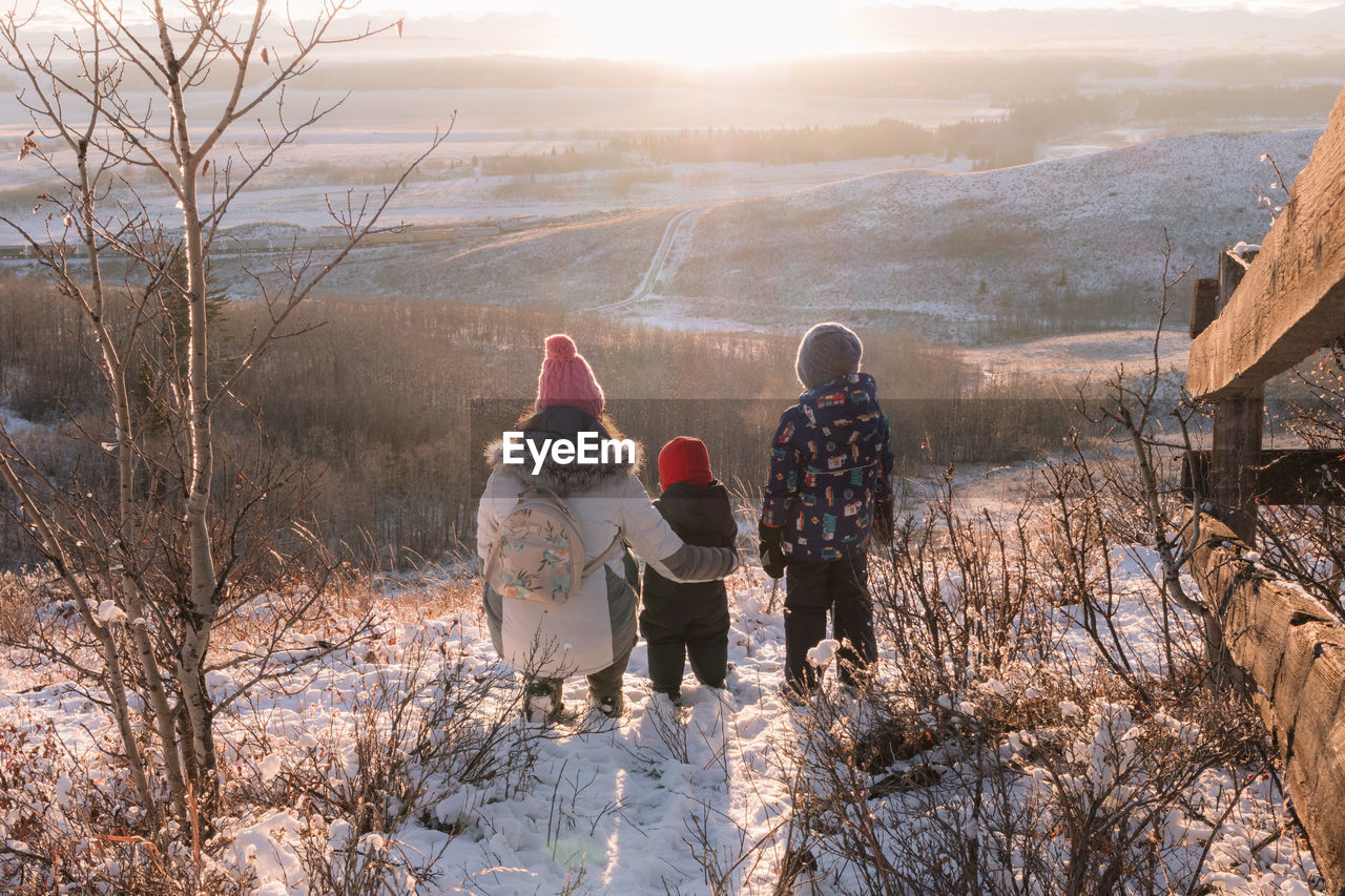 Scenic view of a mom and her children looking at the snowy landscape at sunset