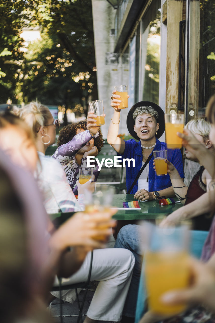 Happy young man enjoying drink while sitting with friends