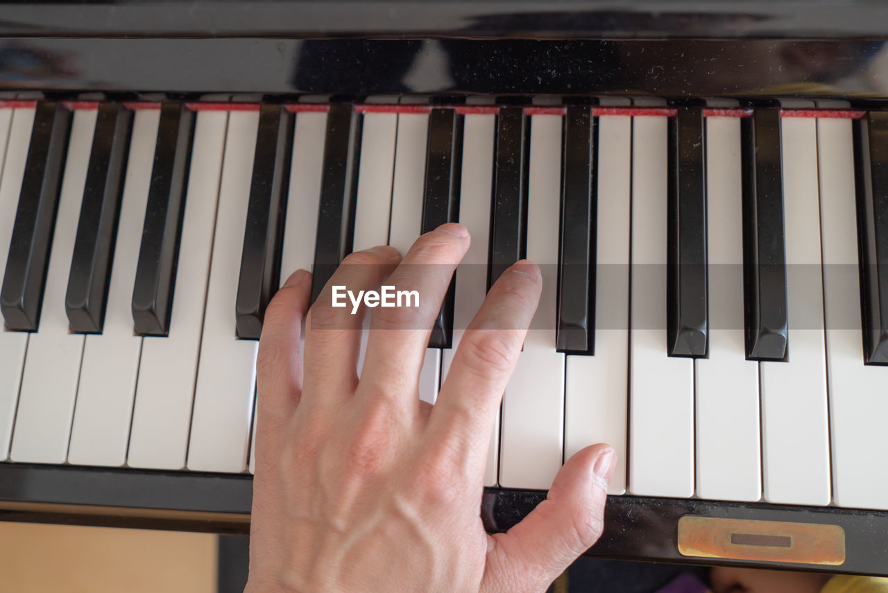 Cropped hand playing piano indoors