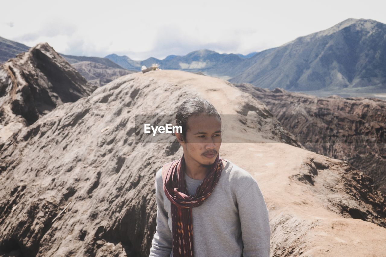 Young man standing on mountain against sky