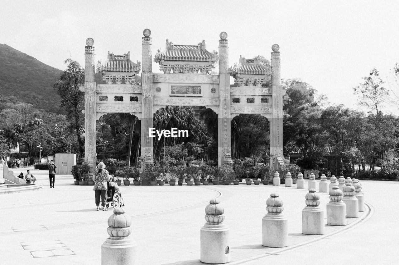 GROUP OF PEOPLE IN FRONT OF BUILT STRUCTURE AGAINST SKY