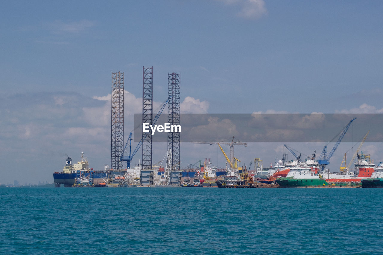 Cranes at harbor against sky