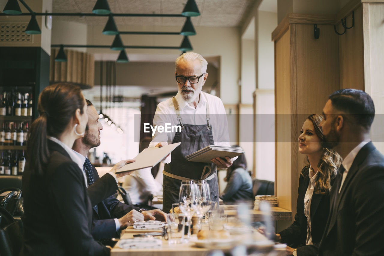 Waiter giving menu to business people in restaurant