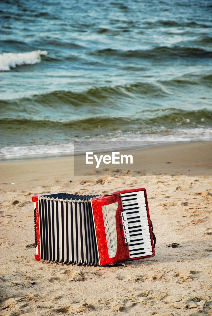 Red accordion on sand at beach