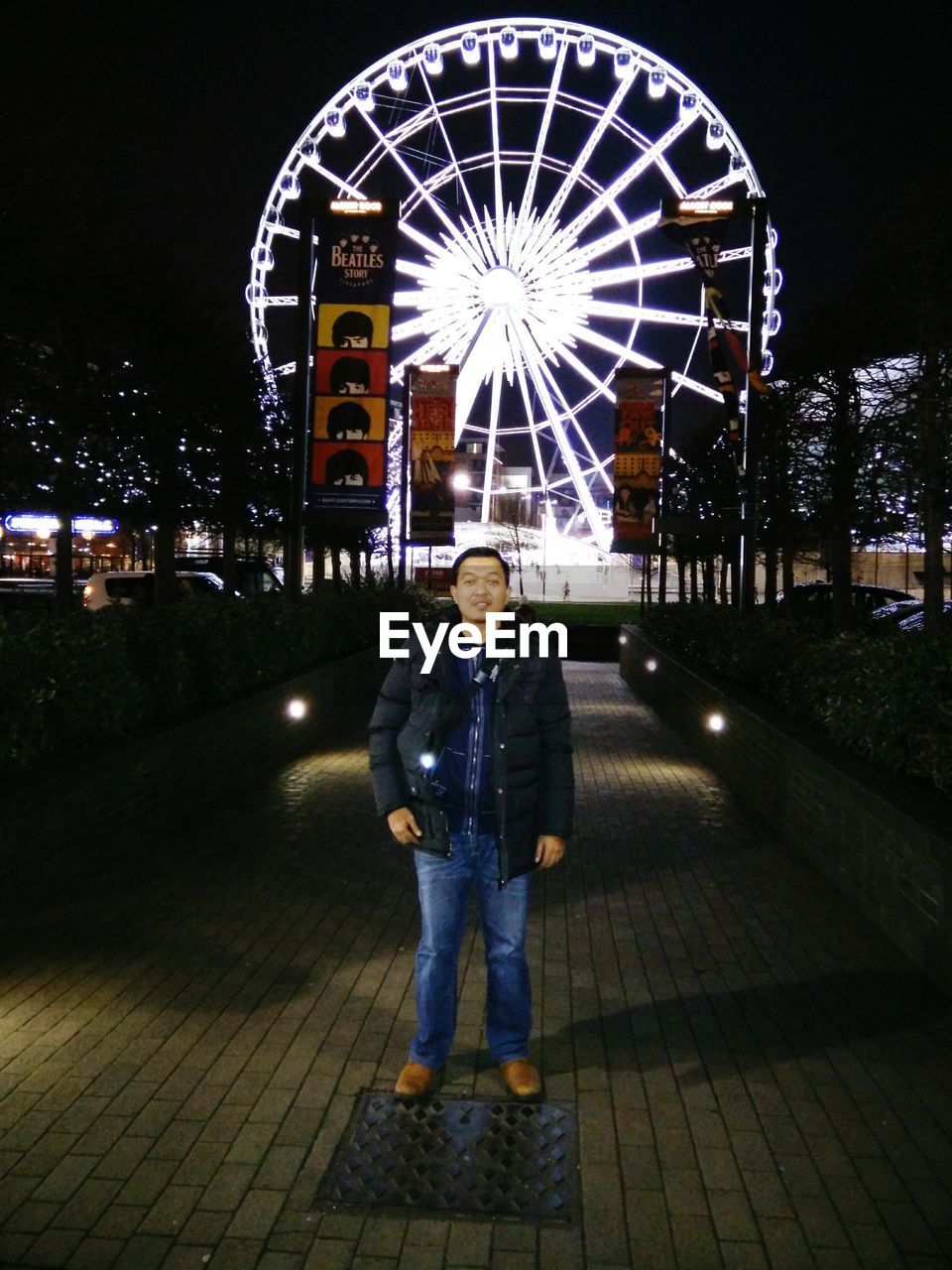 PORTRAIT OF SMILING MAN STANDING AGAINST ILLUMINATED BUILDING