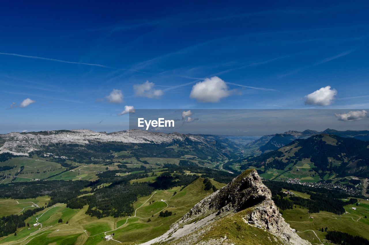 Aerial view of landscape and mountains against blue sky