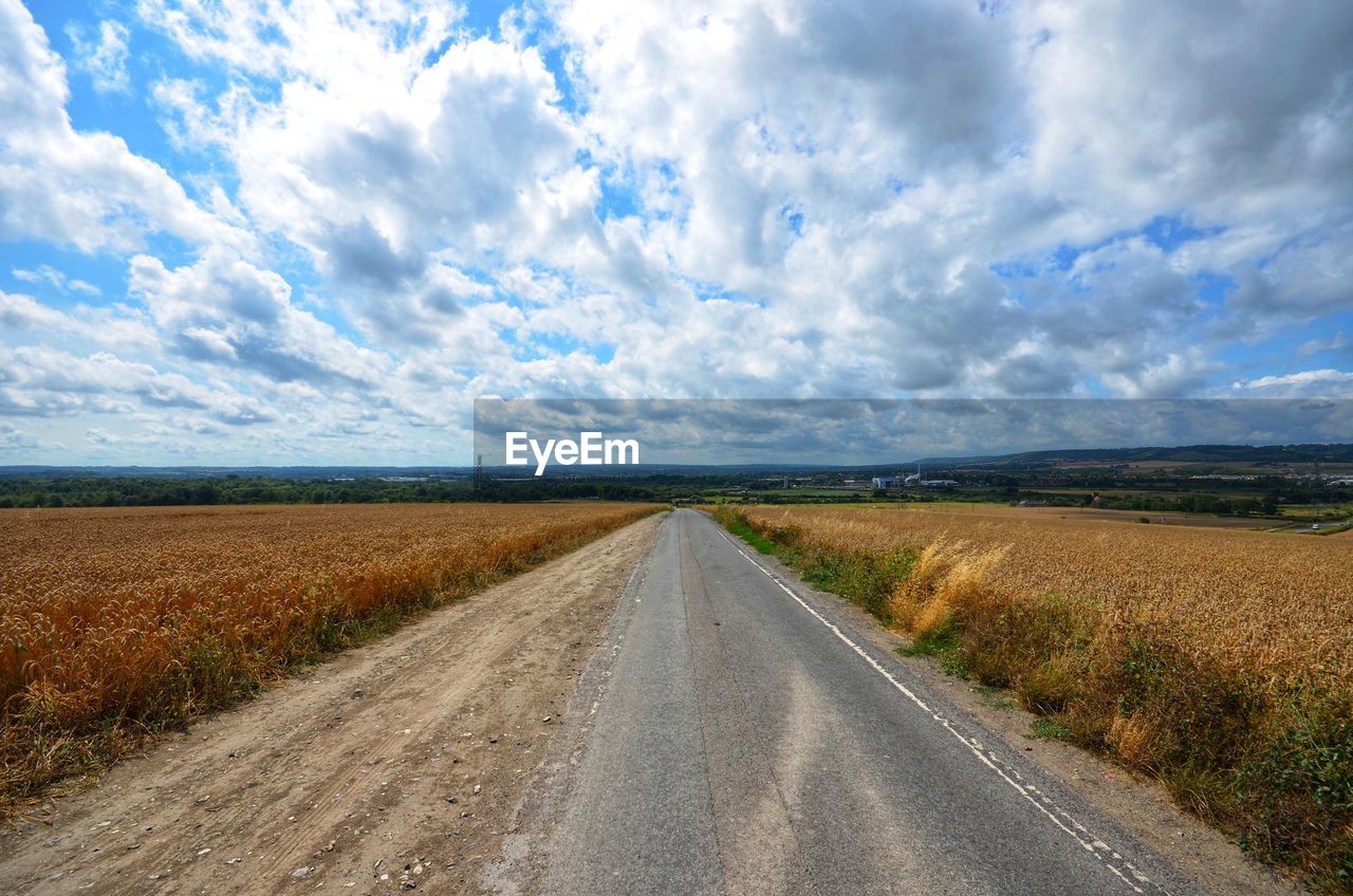 Road amidst field against sky