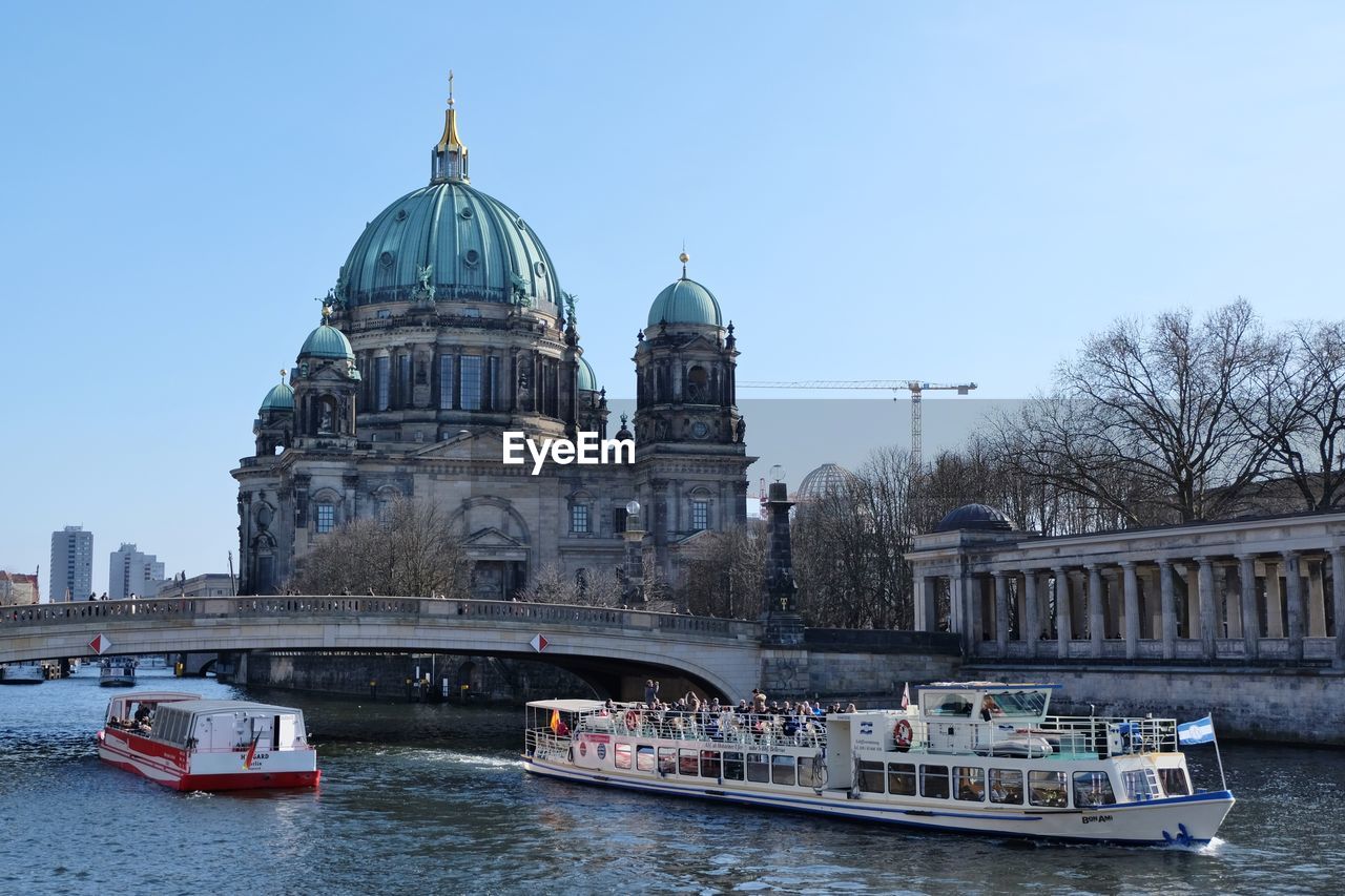 Ferry boats sailing in spree river against berlin cathedral