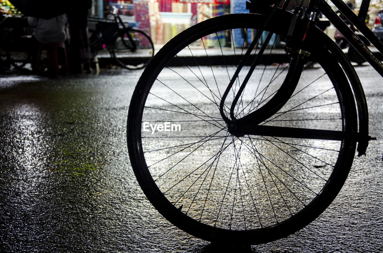 Cropped silhouette bicycle on street in rainy season