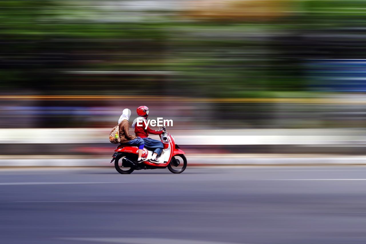 BLURRED MOTION OF MAN RIDING MOTORCYCLE ON ROAD