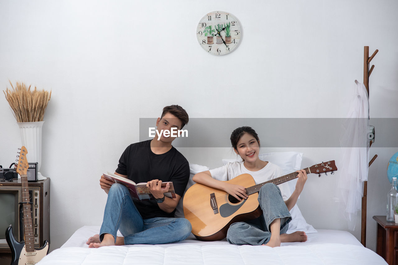 YOUNG COUPLE SITTING AT GUITAR