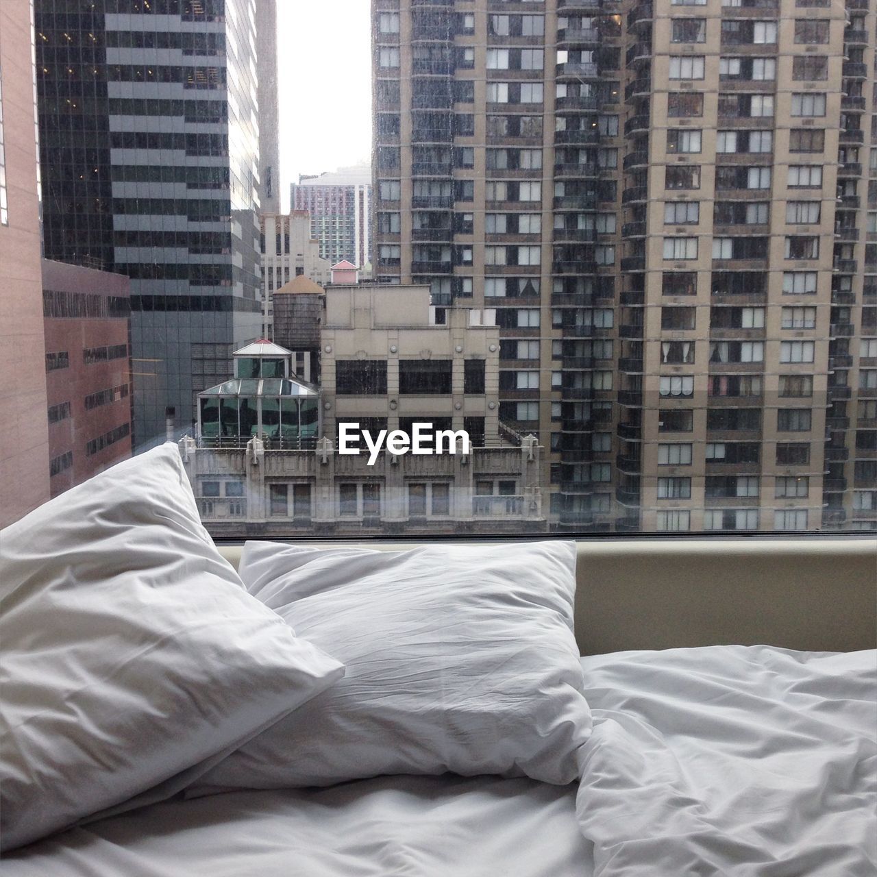 Bed and cushion by window with buildings in background