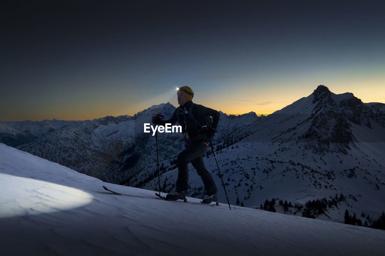 Man with headlamp walking on snowy mountain