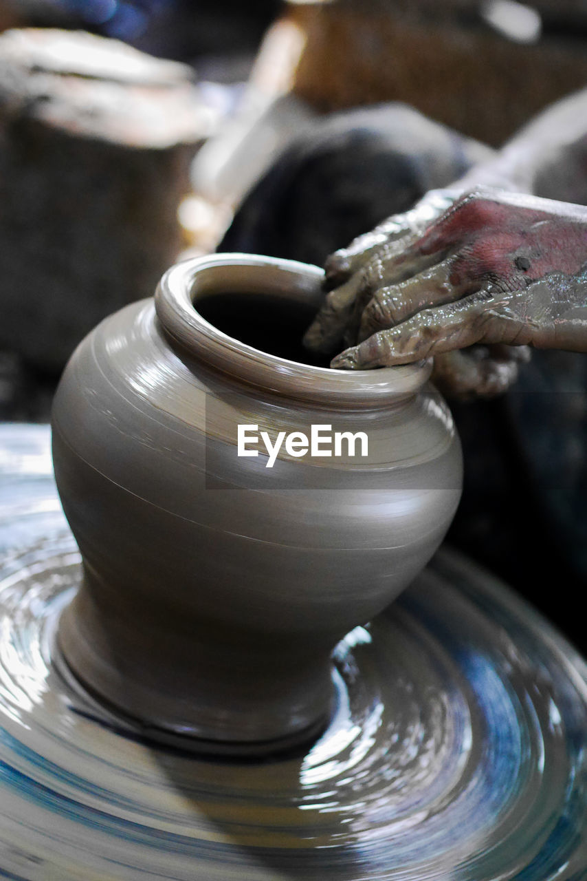 Midsection of person molding pottery on pottery wheel