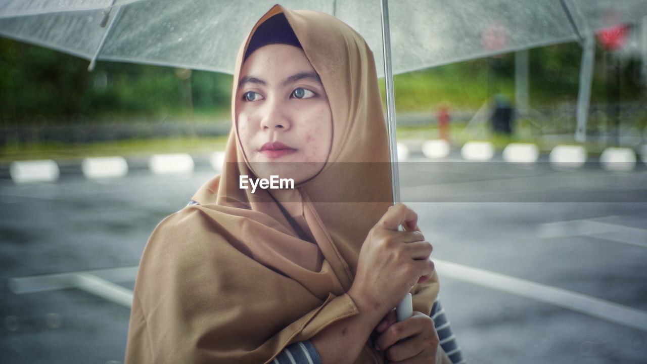 Woman in headscarf holding umbrella 