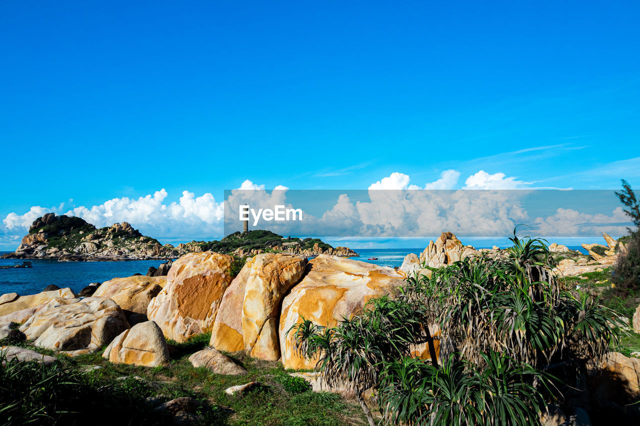 Panoramic view of rocks and sea against blue sky