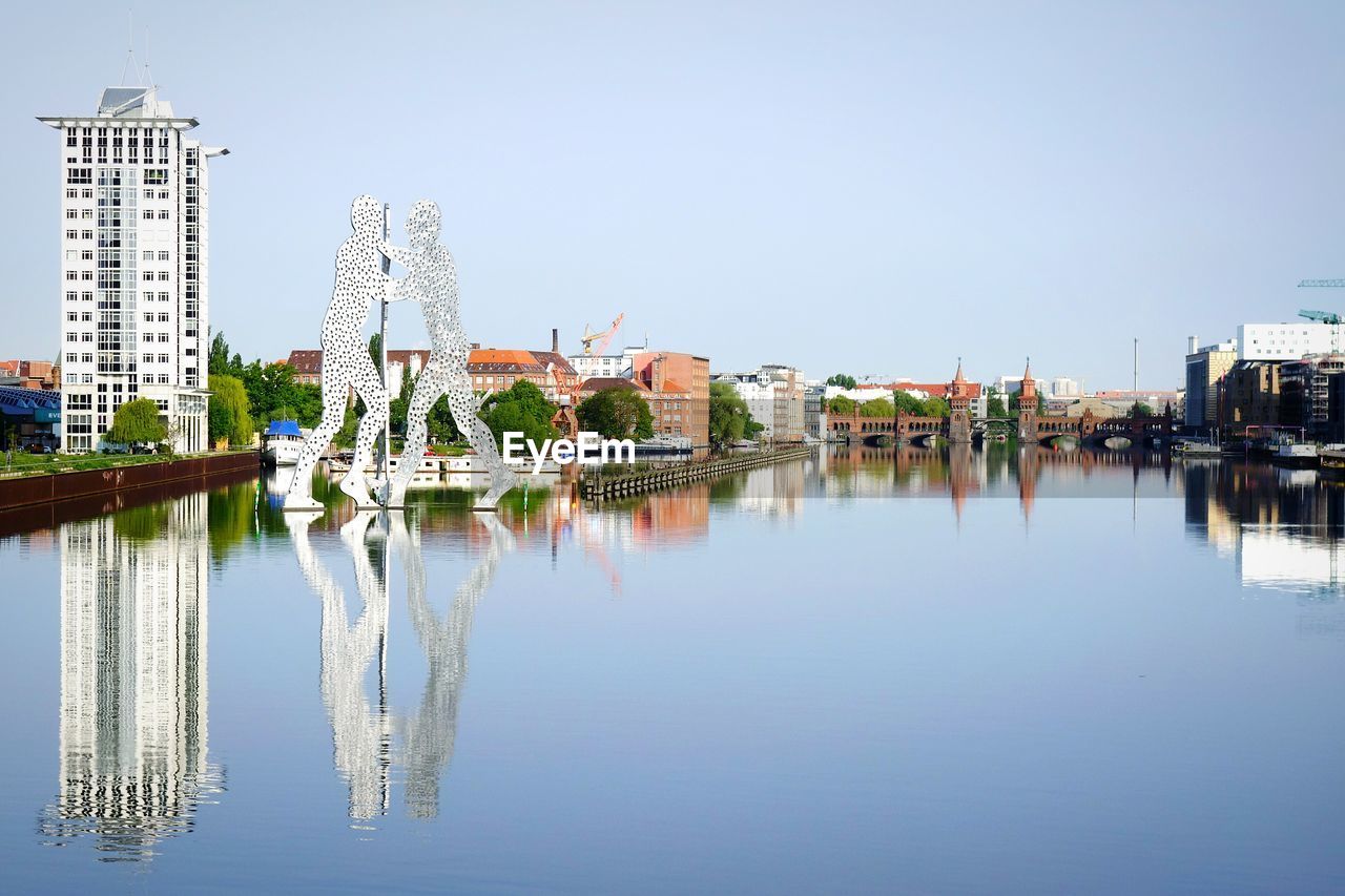 Molecule men statue on spree river against clear sky