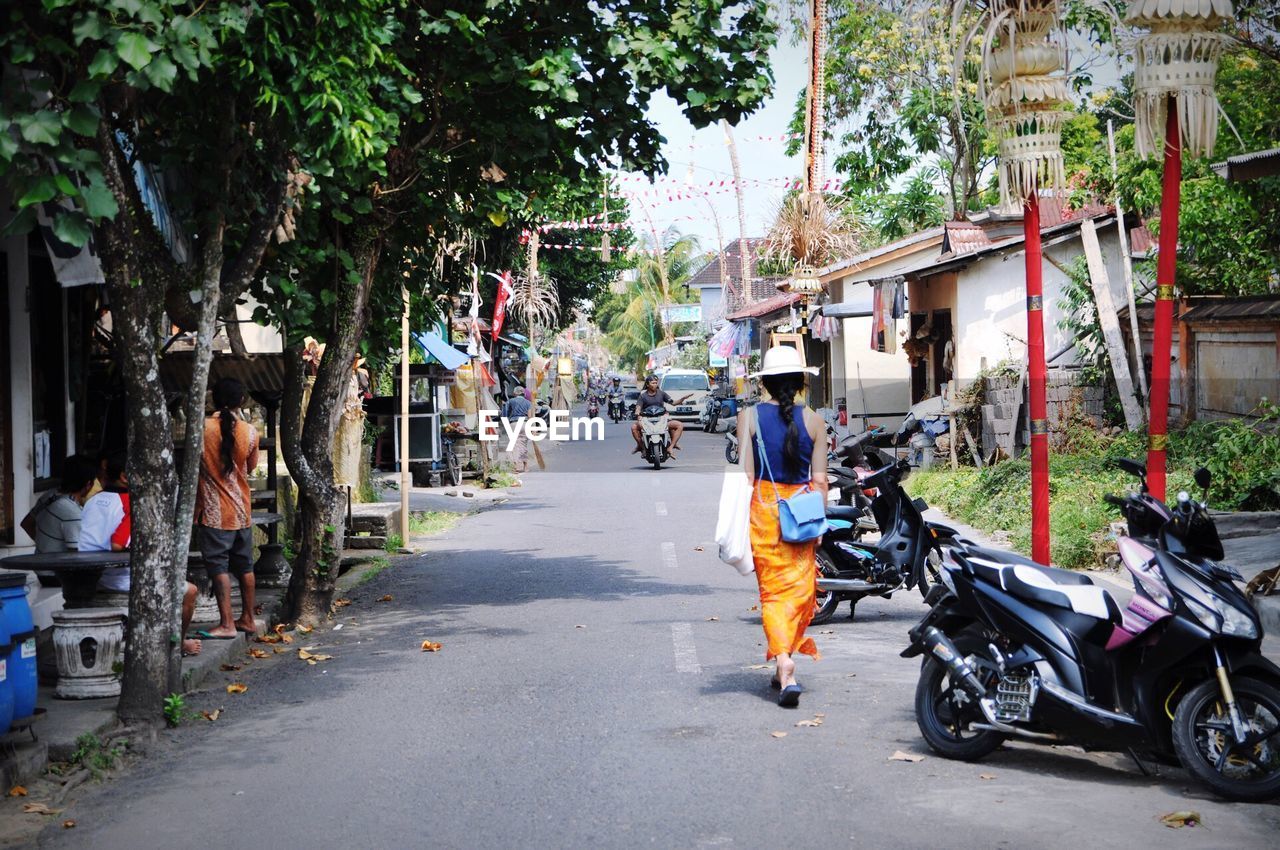 PEOPLE WALKING ON ROAD ALONG BUILDINGS