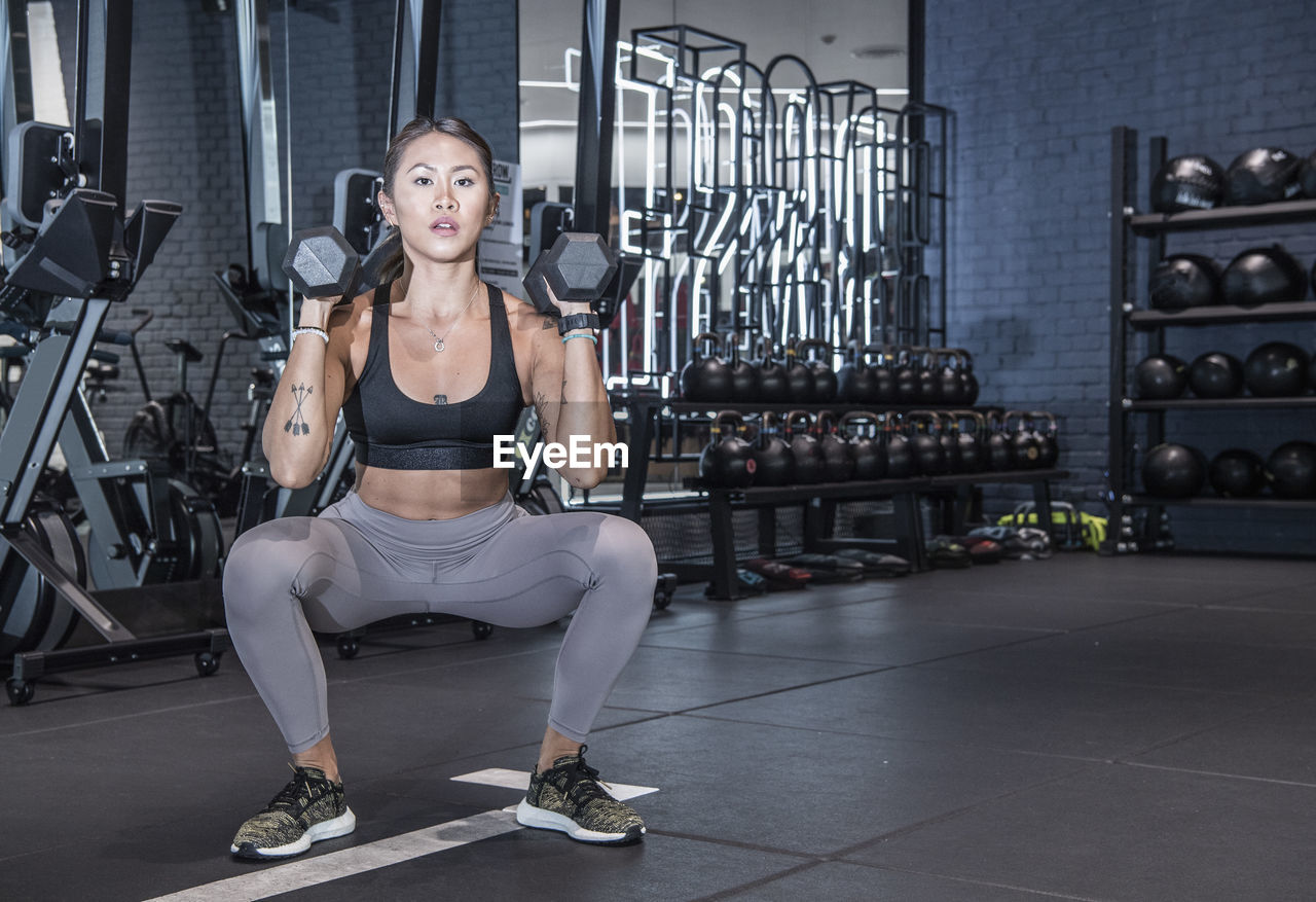 Woman working out with dumbells in urban gym in bangkok