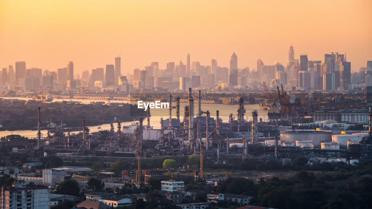 HIGH ANGLE VIEW OF BUILDINGS IN CITY AGAINST SKY DURING SUNSET