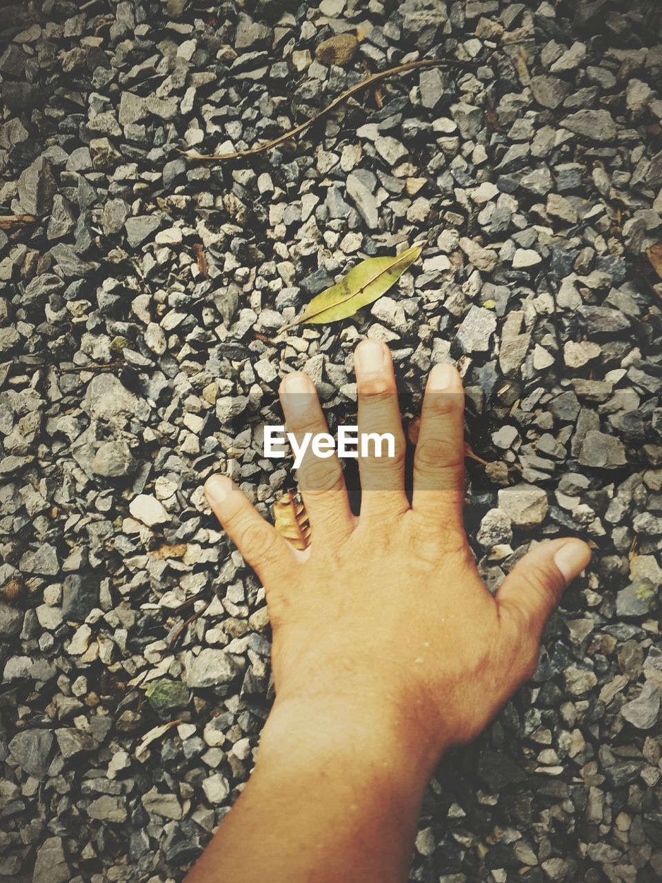 Cropped image of hand touching stones