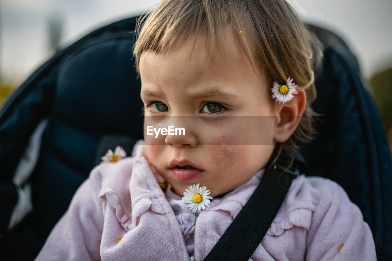 Close up portrait of little child with blond hair and small flowers