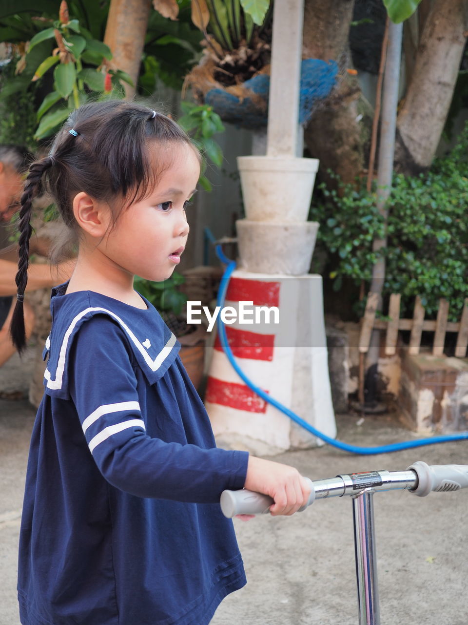 Side view of girl looking away while standing by push scooter