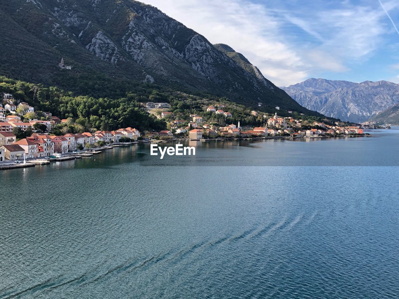 Town by lake and mountains against sky