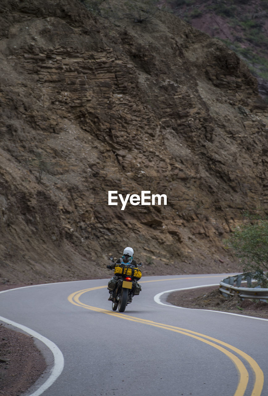 Woman on touring motorbike riding twisting road in argentina