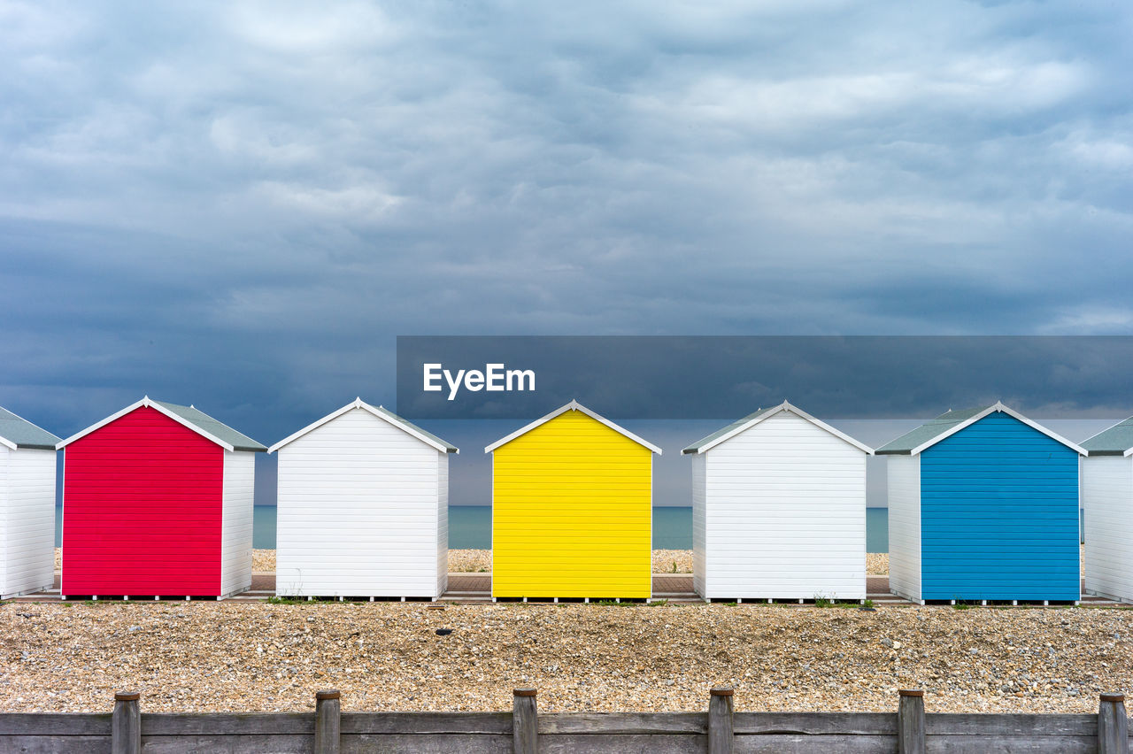 Colorful beach huts against cloudy sky