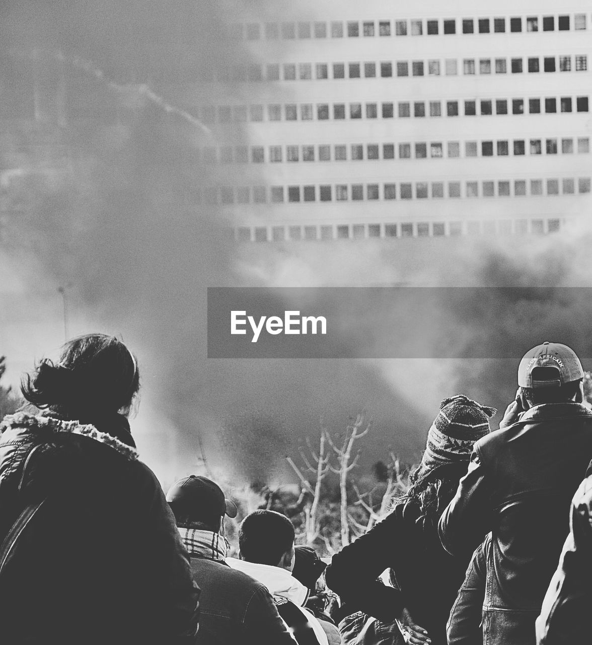 People watching building surrounded by smoke