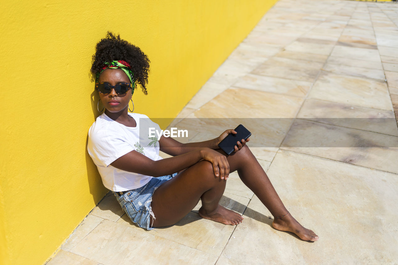 High angle view of young woman sitting on floor against wall