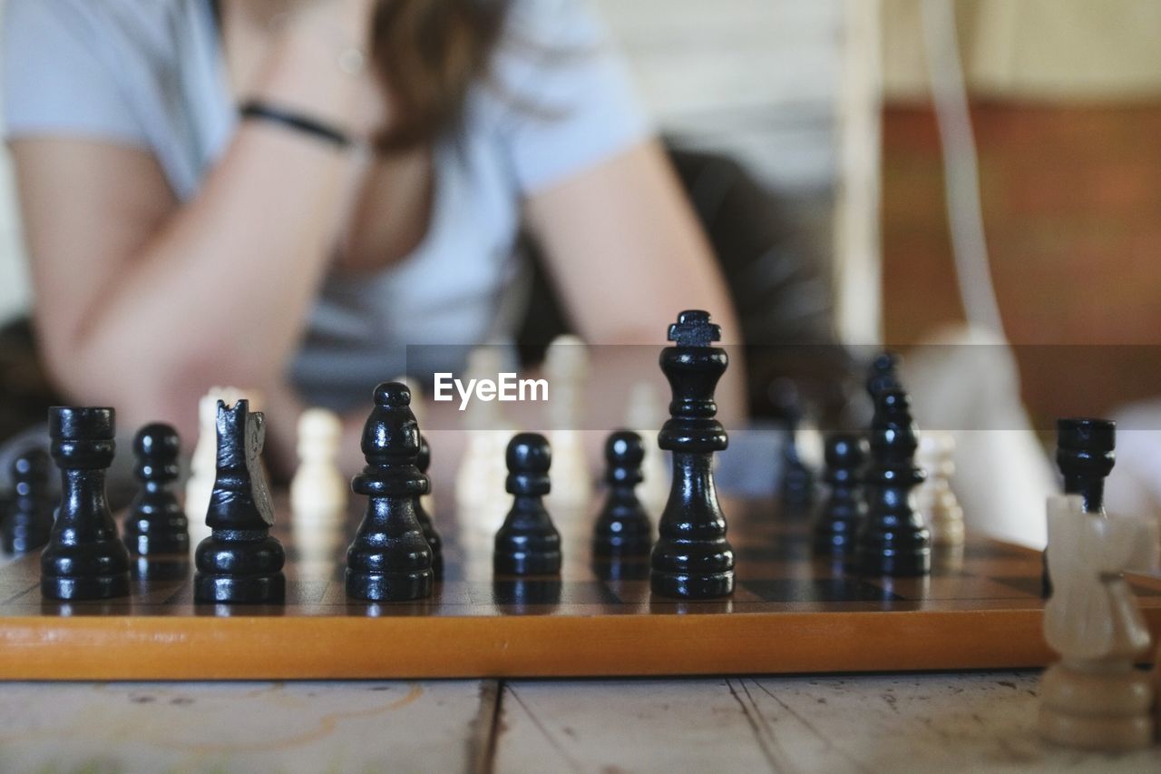 Midsection of woman playing chess on table