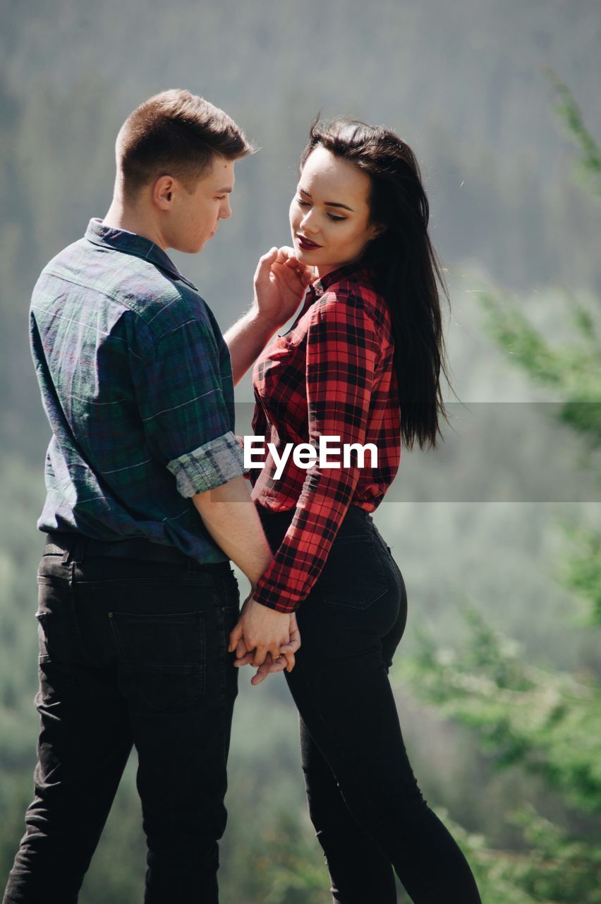 Loving young couple standing in forest