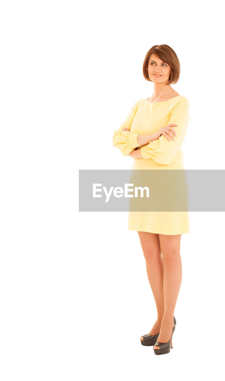 Full length of smiling woman in yellow dress against white background