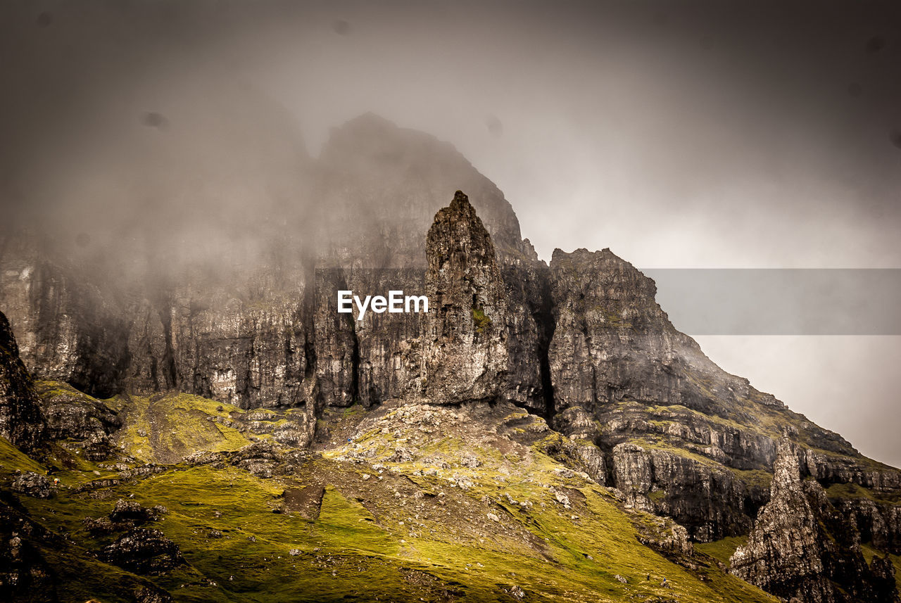 Scenic view of cliffs under cloudy sky