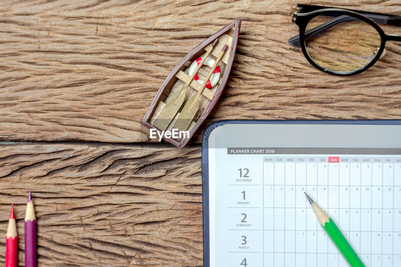 Directly above shot of diary with pencils and toy boat on table