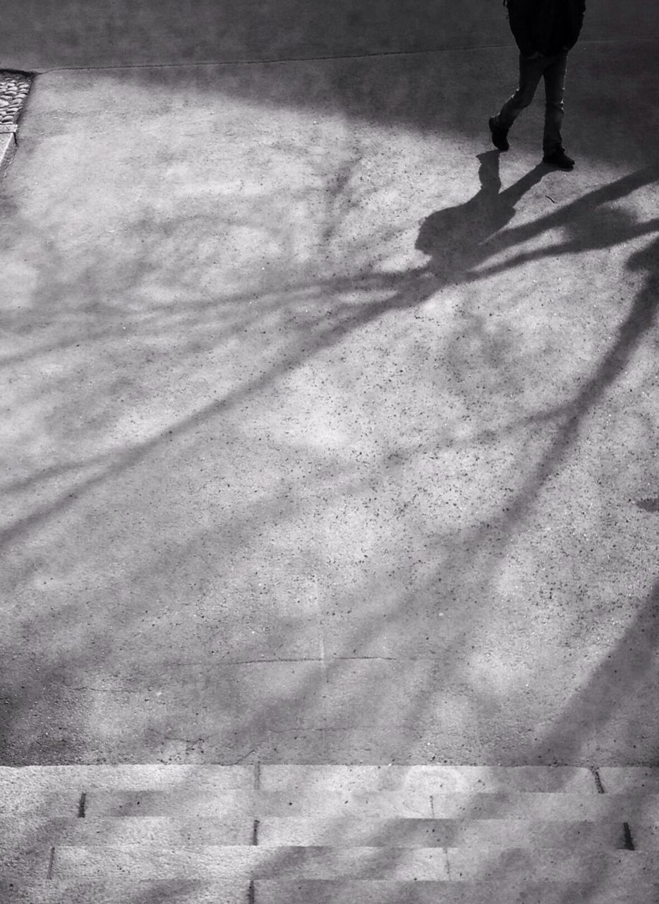 Low section of silhouette person walking on road