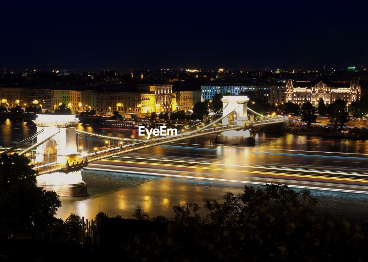 ILLUMINATED BRIDGE OVER RIVER IN CITY