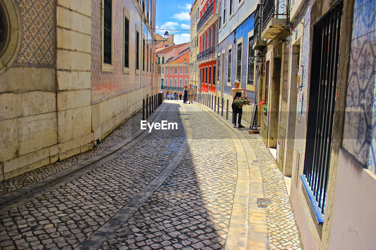 PEOPLE ON FOOTPATH AMIDST BUILDINGS