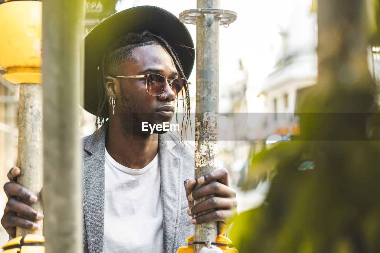 PORTRAIT OF YOUNG MAN LOOKING AWAY WHILE OUTDOORS