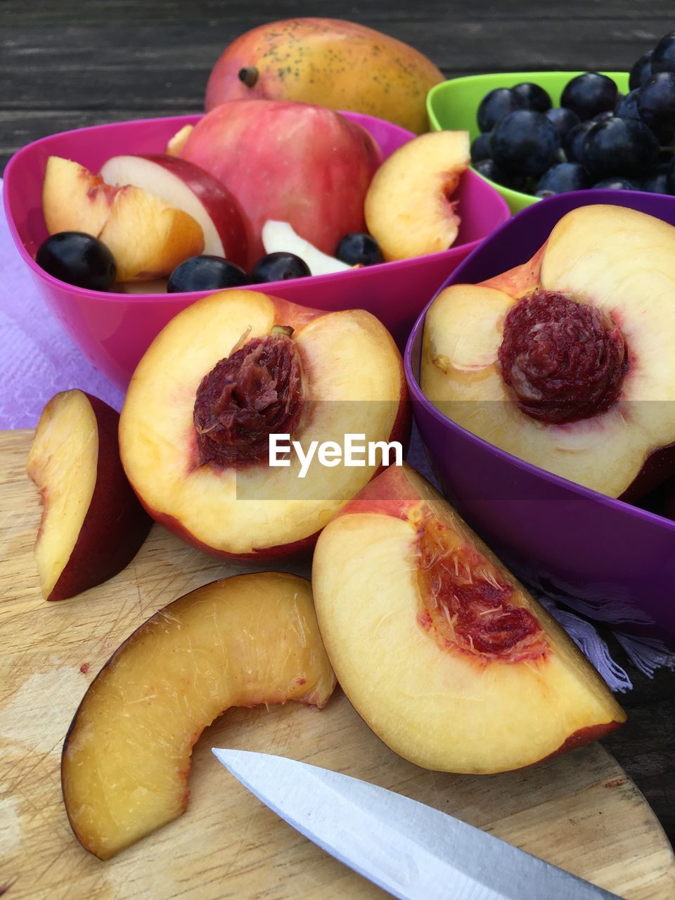 Close up of cut nectarines and bowls of fruit