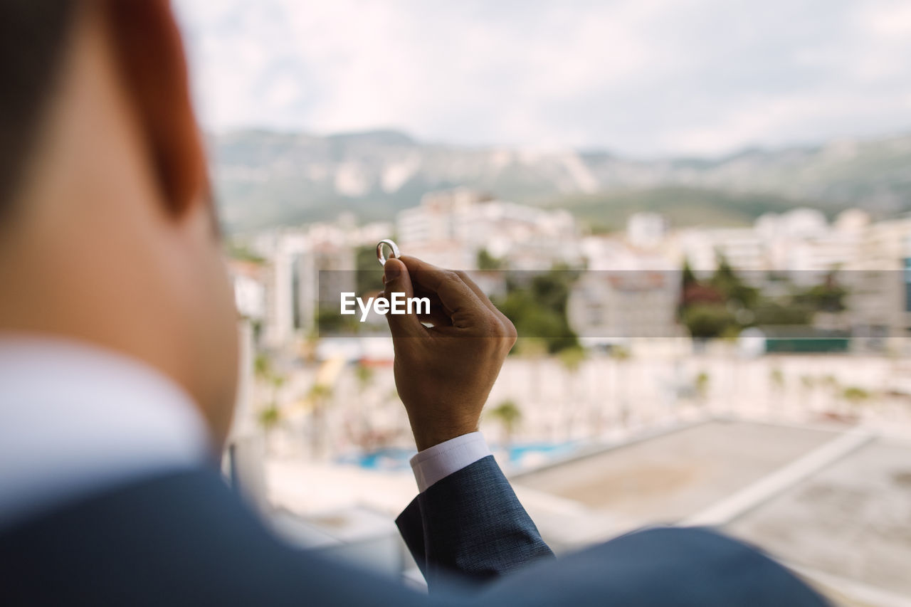 Rear view of groom holding wedding ring